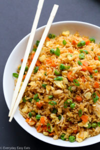 Close-up overhead view of Chinese Fried Rice in a white plate on a dark background.