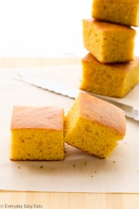 Side view of sliced Cornbread Without Buttermilk on a wooden chopping board.