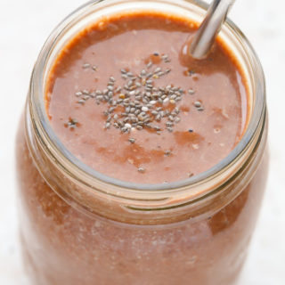 Overhead view of a mason jar full of Healthy Chocolate Milkshake with a straw against a light background.