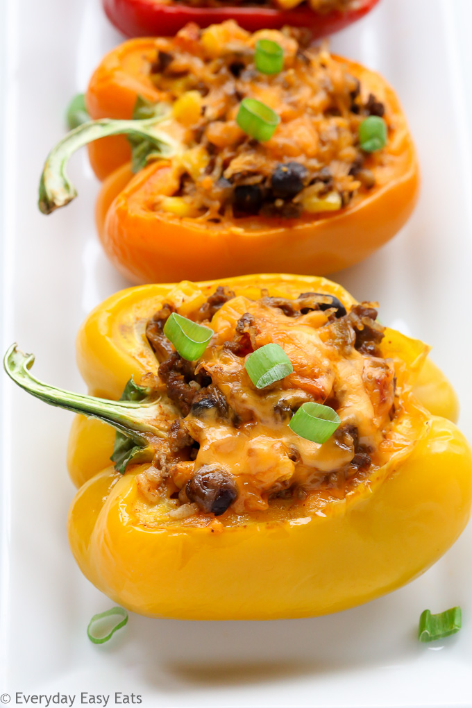 Close-up side view of Mexican stuffed peppers with ground beef in a white serving dish.