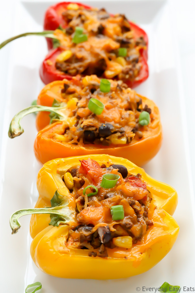 Overhead view of three Mexican stuffed peppers with ground beef in a white serving dish.