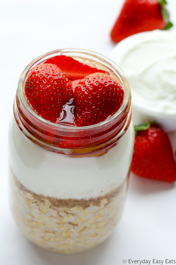 Overhead view of Strawberry Overnight Oats with Yogurt in a mason jar on a white background.