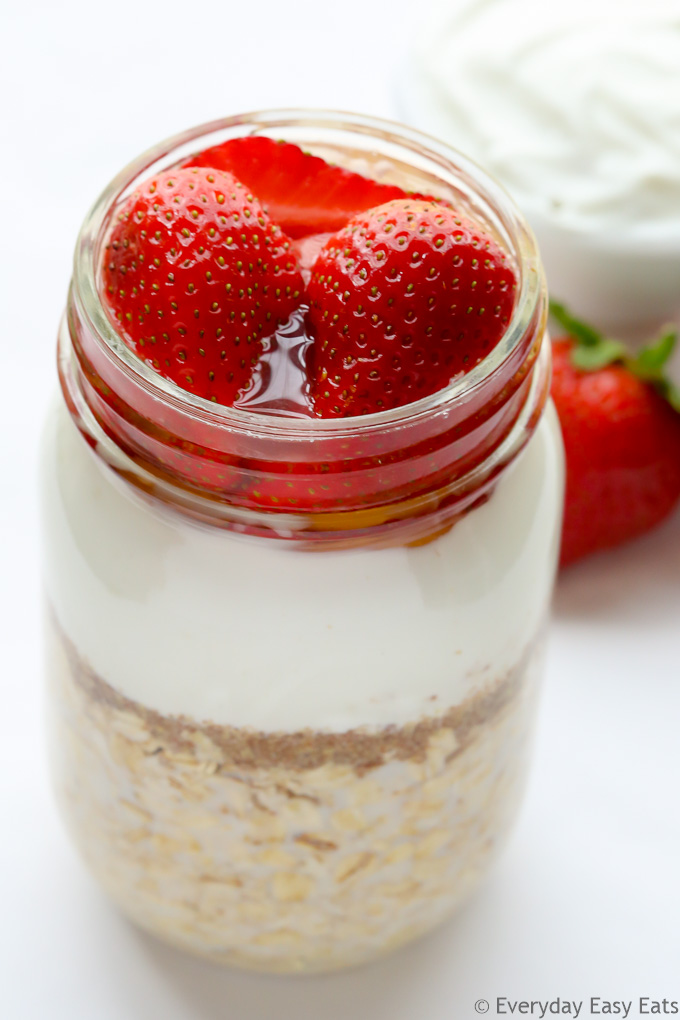 Close-up overhead view of Strawberry Overnight Oats with Yogurt in a mason jar on a white background.