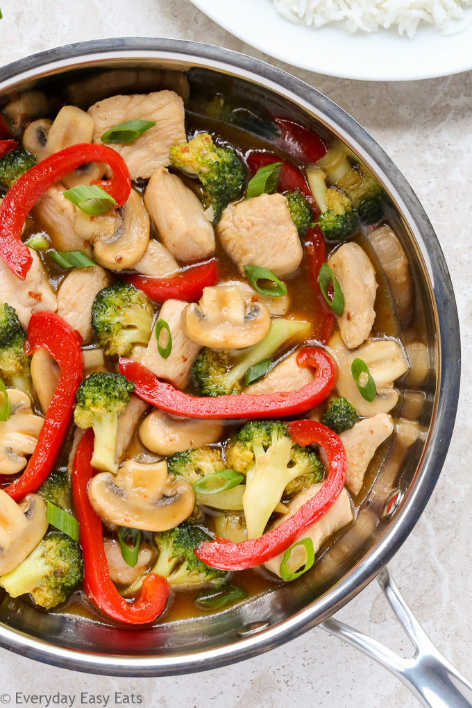 Close-up overhead view of Healthy Chicken Stir-Fry in a wok on a neutral-colored background.