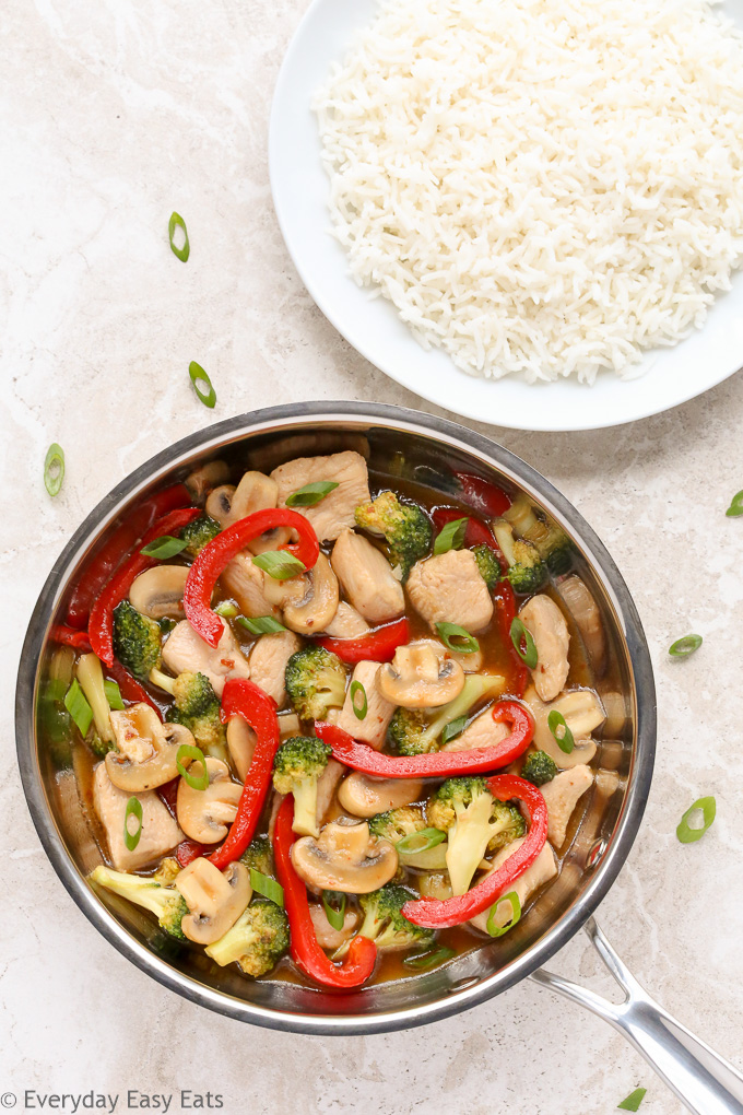 Overhead view of Chicken Stir-Fry with Vegetables in a wok with a plate of white rice beside it.