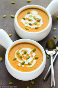 Curried Coconut Pumpkin Soup in white bowls with spoons on black background