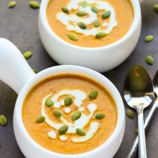 Curried Coconut Pumpkin Soup in white bowls with spoons on black background