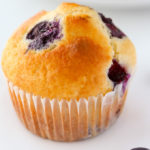 Close-up overhead view of a blueberry muffin on a white background.