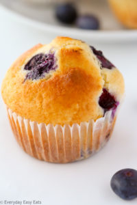 Close-up overhead view of a blueberry muffin on a white background.