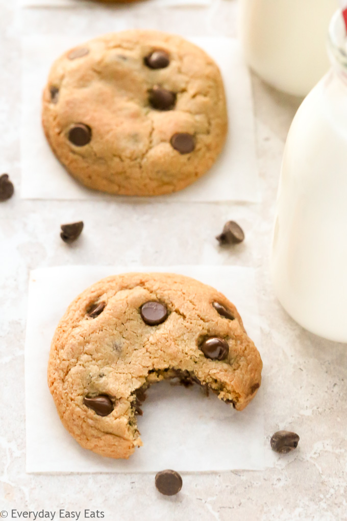 Close-up overhead view of a Chocolate Chip Cookie with a bite taken out of it on a neutral background.