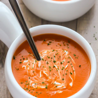 Close-up overhead view of two bowls of Cream of Tomato Soup against a wooden background.
