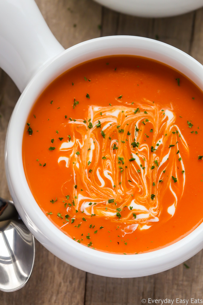 Close-up overhead view of a bowl of Cream of Tomato Soup against a wooden background.