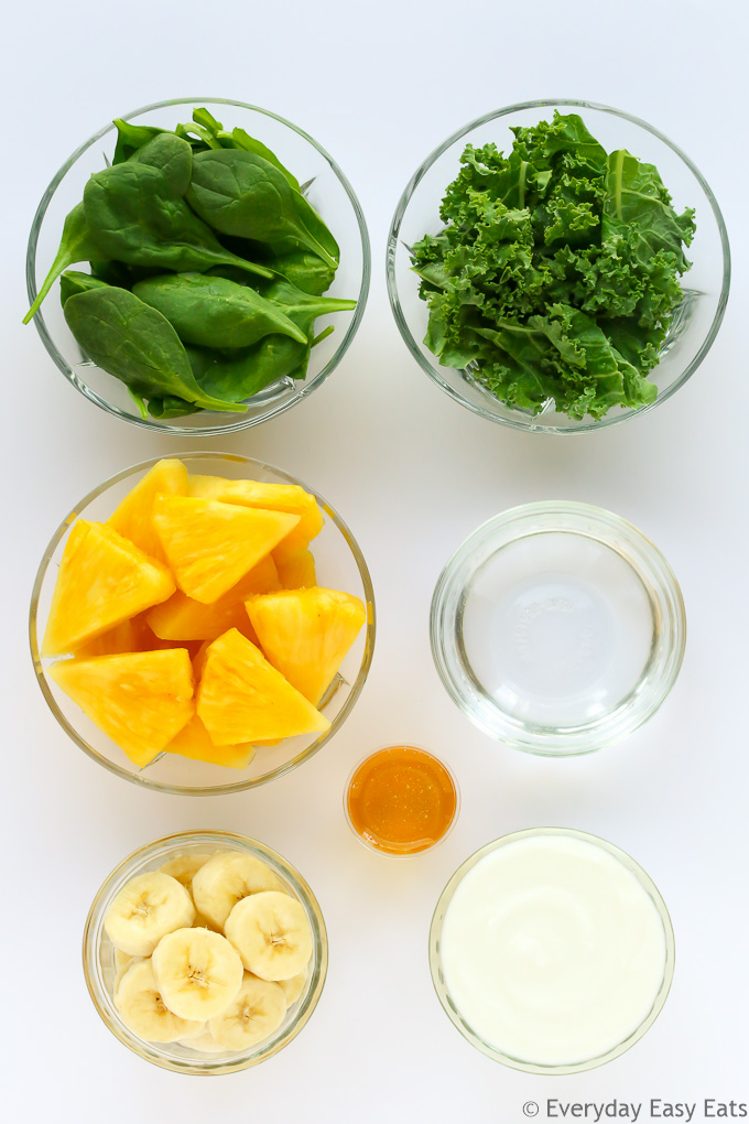 Overhead view of Green Smoothie ingredients in glass bowls on a light background.