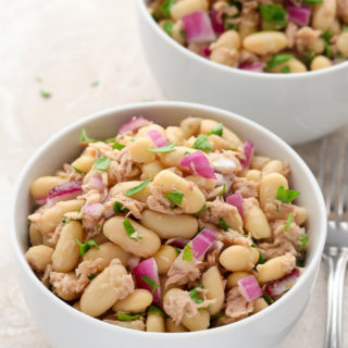 Overhead view of two bowls of Tuna White Bean Salad on a neutral-colored background.