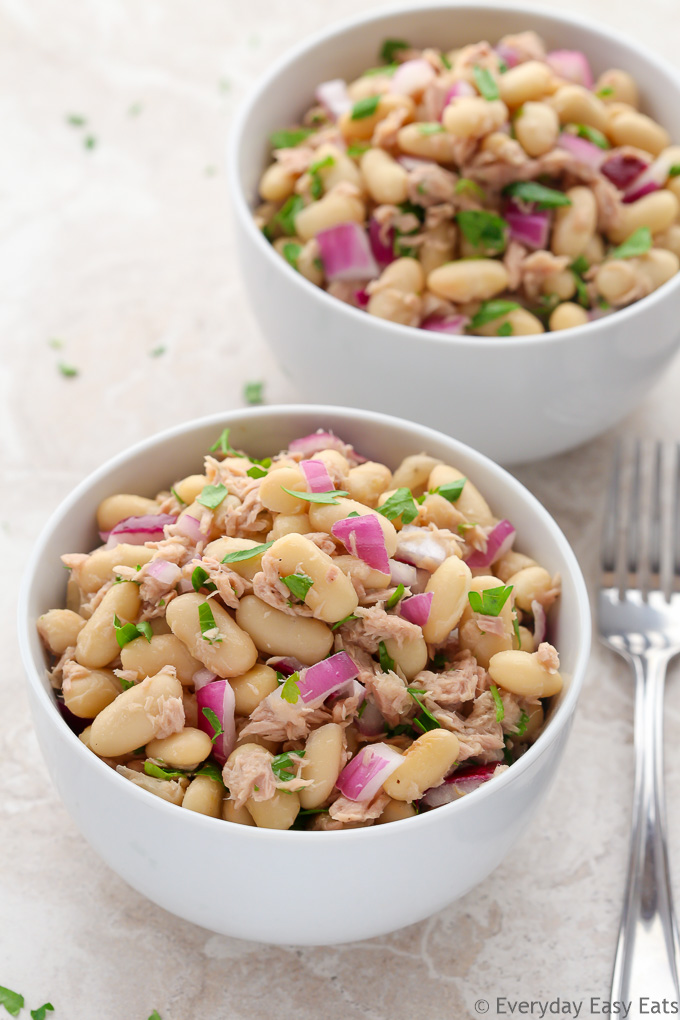 Overhead view of two bowls of Tuna White Bean Salad on a neutral-colored background.