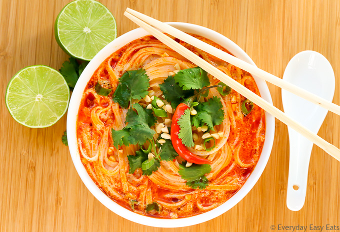 Overhead view of Thai Spicy Noodle Soup in a white bowl with chopsticks on a wooden background.