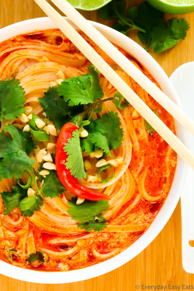 Close-up overhead view of Thai Noodle Soup in a white bowl on a wooden background.