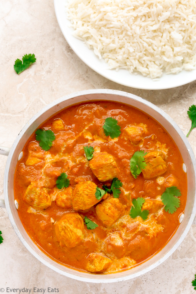 Close-up overhead view of Quick Indian Chicken Curry in a silver serving bowl with a plate of white rice.