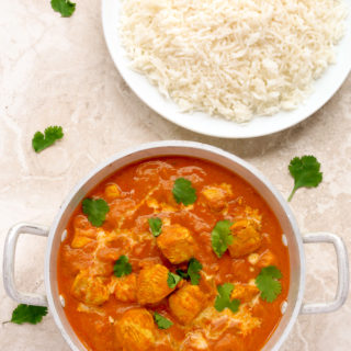 Overhead view of Quick Indian Chicken Curry in a silver serving bowl with a plate of white rice.