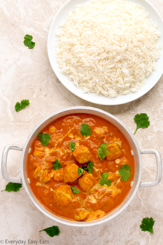 Overhead view of Quick Indian Chicken Curry in a silver serving bowl with a plate of white rice.