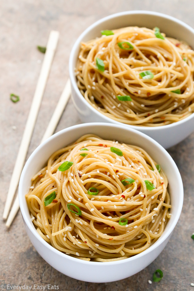 Overhead view of two bowls of Easy Sesame Noodles with chopsticks on the side on a neutral background.