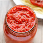 Overhead view of Quick Marinara Sauce in a jar with a plate of pasta in the background