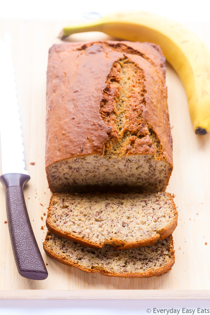 Overhead view of a sliced loaf of Best-Ever Moist Banana Bread on a wooden chopping board.