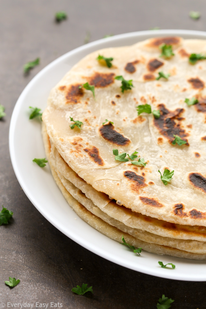 Side view of a stack of Easy Homemade No-Yeast Flatbread in a white plate on a dark background.