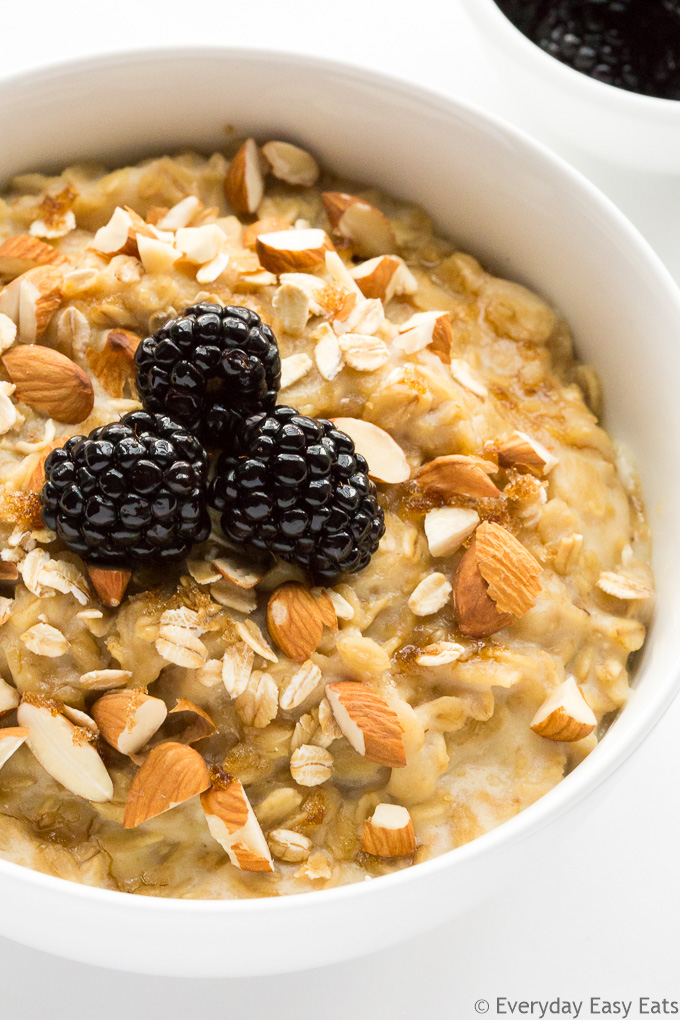 Close-up overhead view of Brown Sugar Oatmeal in a white bowl topped with chopped almonds and blackberries.