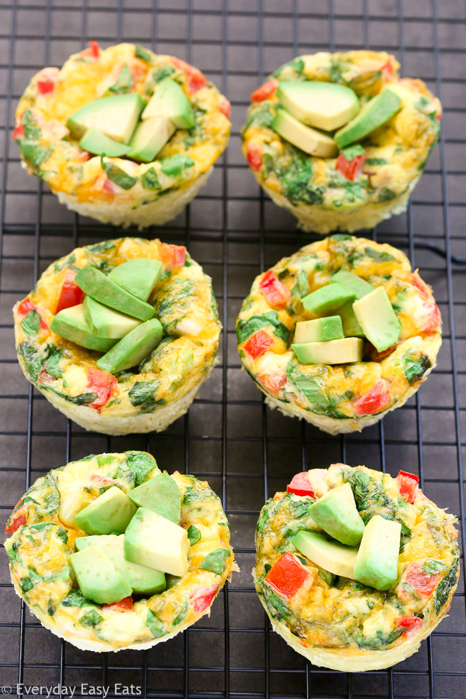 Overhead view of six Breakfast Egg Muffins cooling a on wire rack set above a dark background.