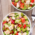 Overhead view of two bowls of Chicken Avocado Salad on a beige background with forks on the side.