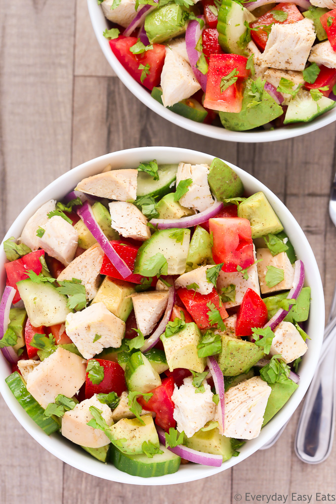 Close-up overhead view of a bowl of Chicken Avocado Salad on a beige background.