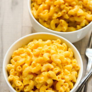 Overhead view of two bowls of Creamy Homemade Macaroni and Cheese on a wooden background.