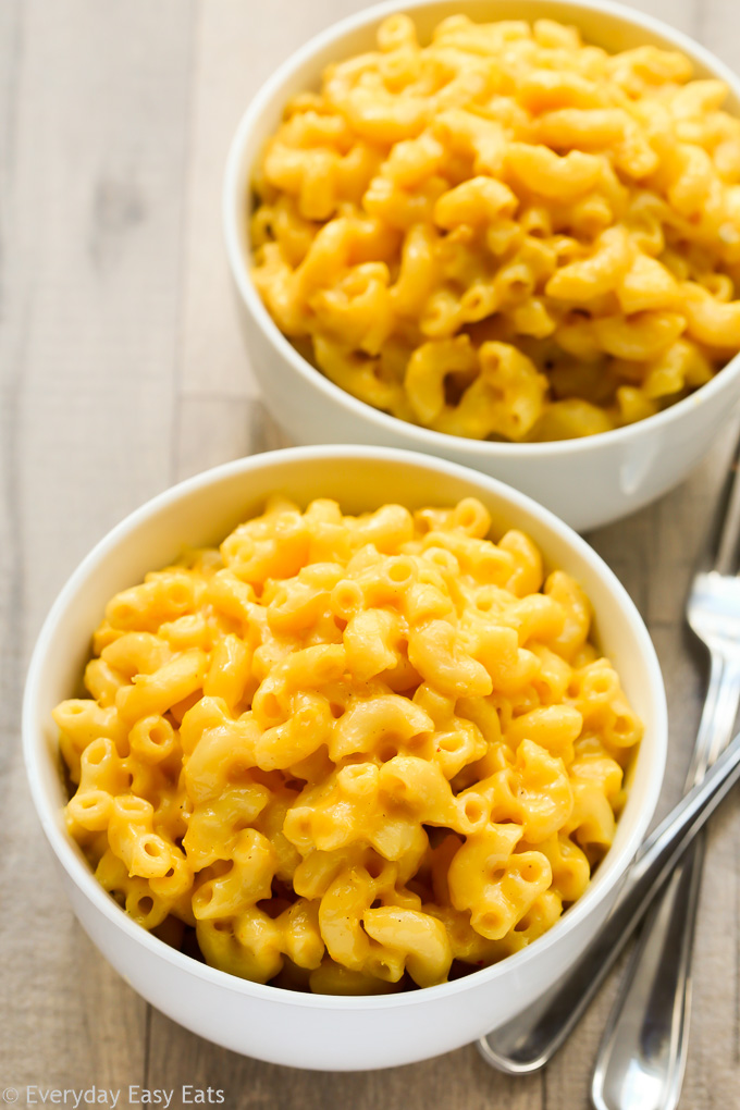 Overhead view of two bowls of Creamy Homemade Macaroni and Cheese on a wooden background.