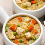 Close-up overhead view of two bowls of One-Pot Chicken and Rice Soup on a beige background.