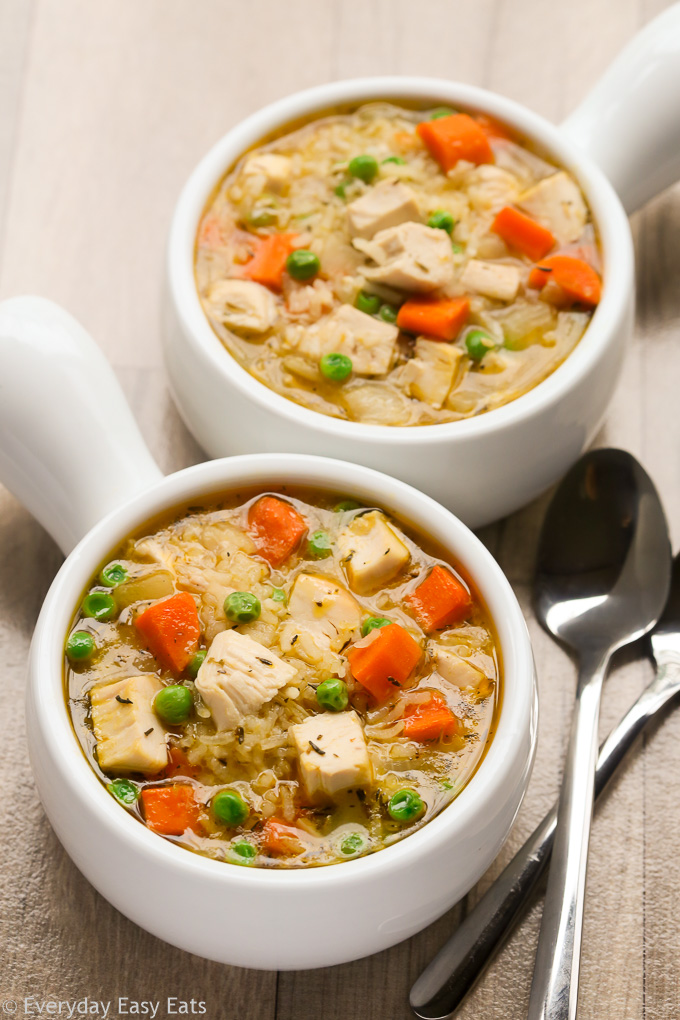 Overhead view of two bowls of One-Pot Chicken and Rice Soup on a beige background.