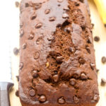 Overhead view of a loaf of Double Chocolate Banana Bread on a wooden chopping board.
