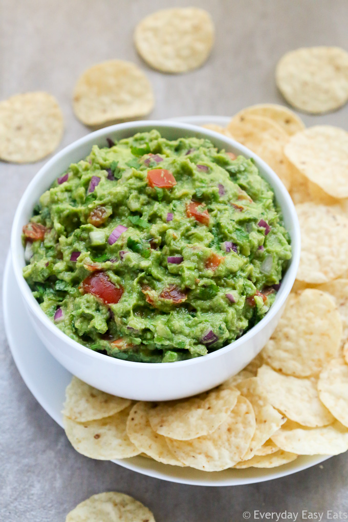 Side view of a bowl of Homemade Guacamole with tortilla chips.