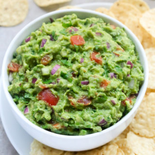 Close-up side view of a bowl of Homemade Guacamole with tortilla chips.