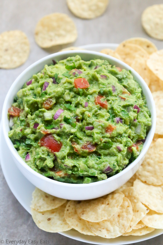 Close-up side view of a bowl of Homemade Guacamole with tortilla chips.