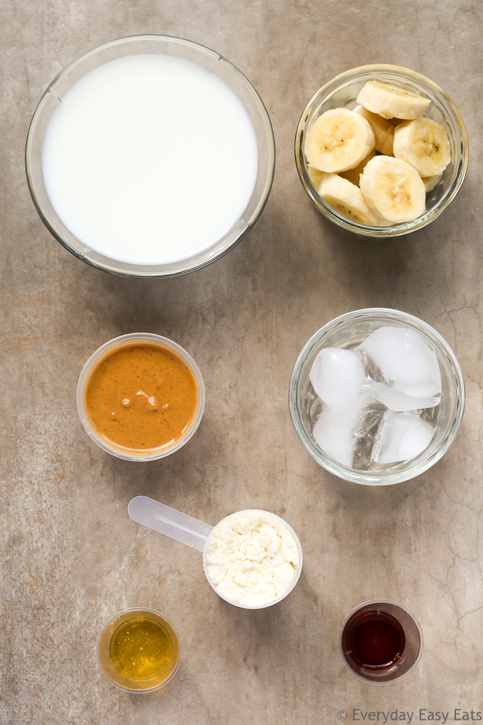 Overhead view of Peanut Butter Banana Protein Shake Recipe ingredients on a beige background.