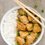 Overhead view of a bowl of Healthy Honey Teriyaki Chicken with rice and chopsticks on a grey background.