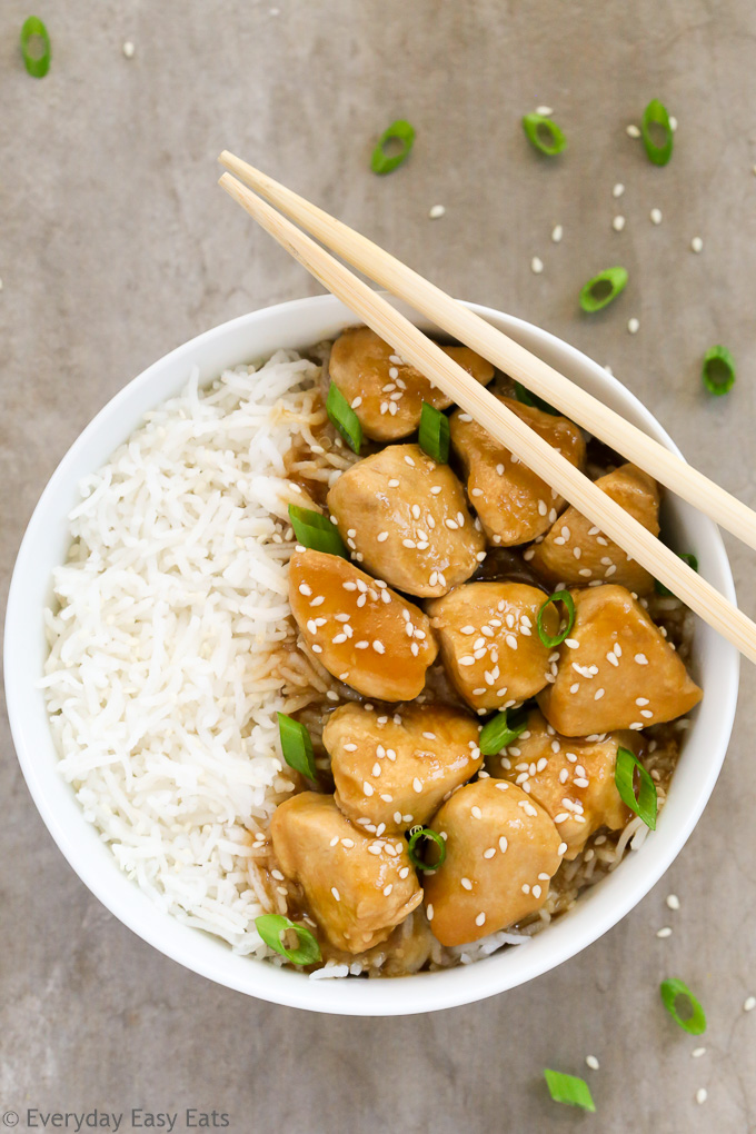 Overhead view of a bowl of Healthy Honey Teriyaki Chicken with rice and chopsticks on a grey background.