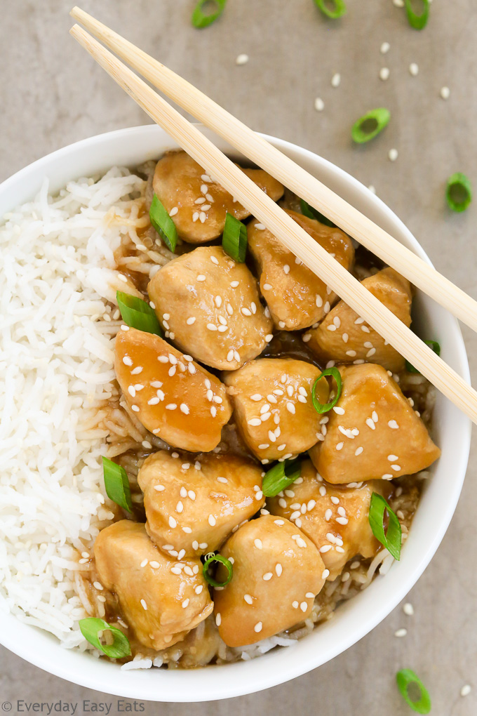 Close-up overhead view of a bowl of Healthy Honey Teriyaki Chicken with rice and chopsticks on a grey background.