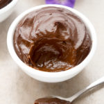 Side view of a bowl of Avocado Chocolate Pudding with a spoonful of pudding taken out and placed in front.