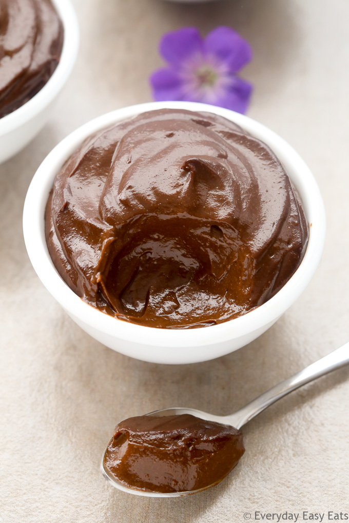 Side view of a bowl of Avocado Chocolate Pudding with a spoonful of pudding taken out and placed in front.