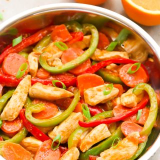 Side overhead view of Healthy Orange Chicken Stir-Fry in a wok on a light background.