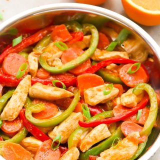 Side overhead view of Orange Chicken Stir-Fry in a wok on a light background.