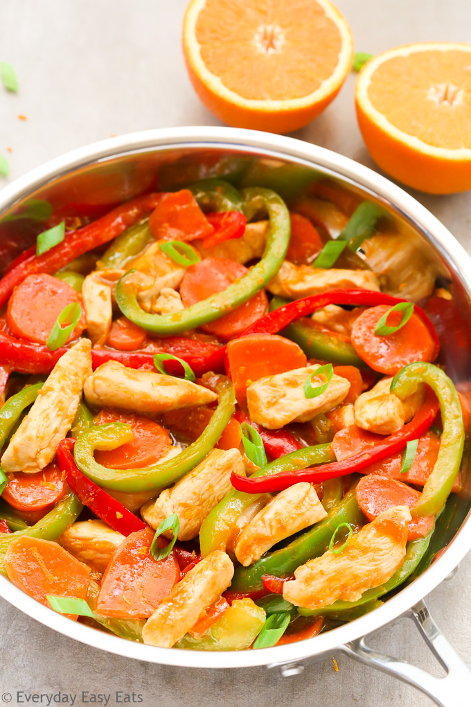 Side overhead view of Orange Chicken Stir-Fry in a wok on a light background.