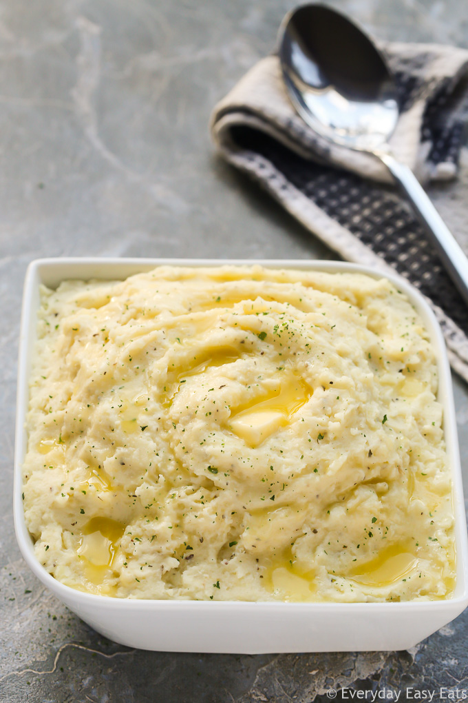 Overhead view of Goat Cheese Mashed Potatoes with a serving spoon on the side on a grey background.